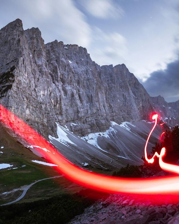 Person moving gracefully in a dark studio with orange light trails.